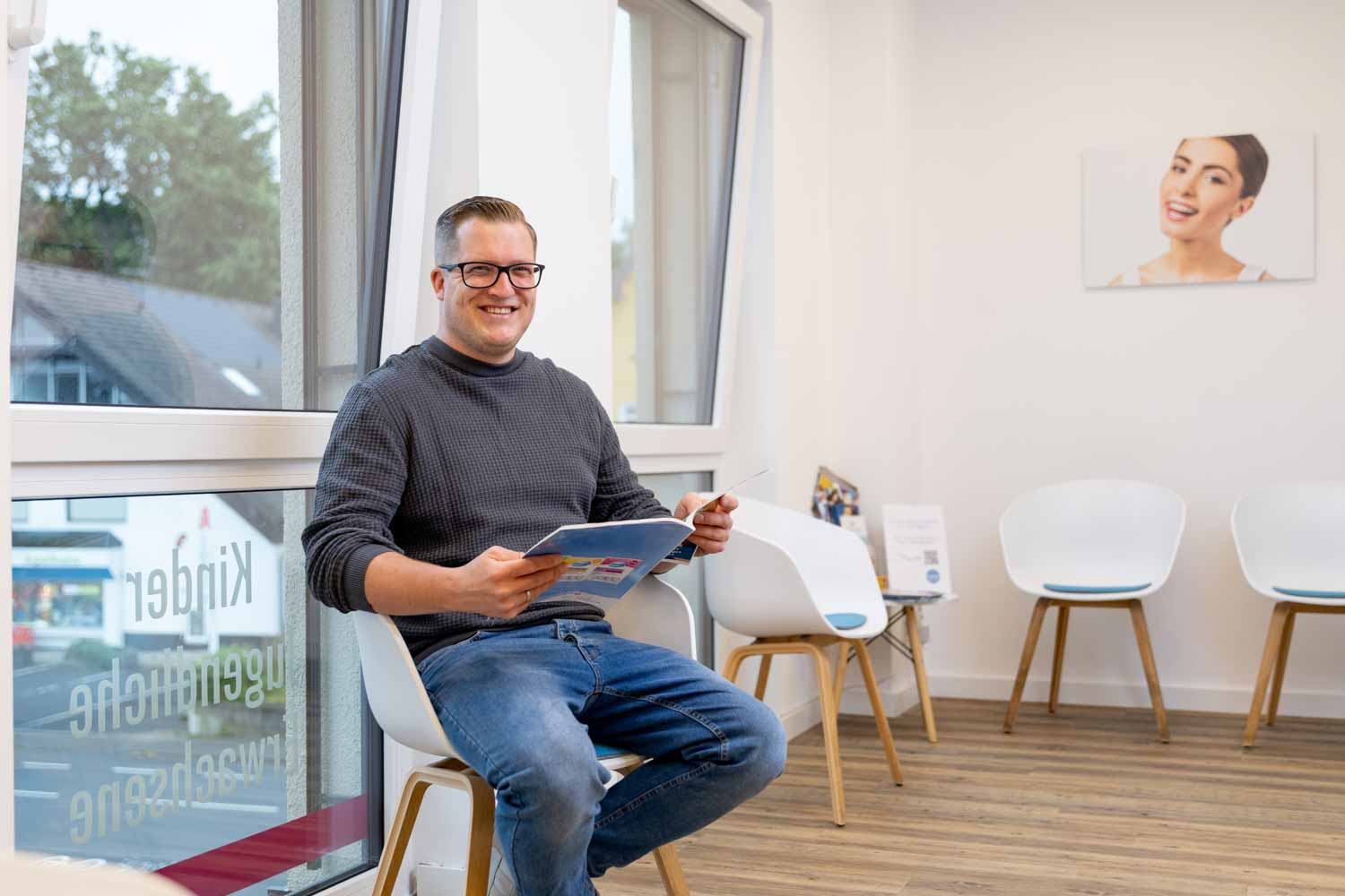Erwachsener Patient liest ein Magazin im hellen Wartezimmer der Kieferorthopädie Seelscheid in Neunkirchen-Seelscheid.