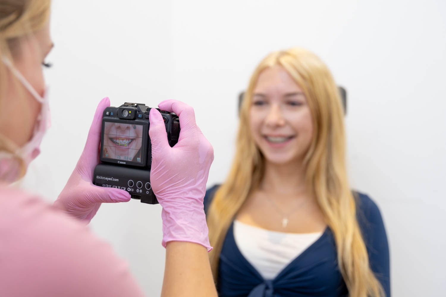 Mitarbeiterin fotografiert mit einer speziellen Kamera mit Ringlicht die Zähne einer lächelnden jungen Patientin zur Behandlungsdokumentation in der Kieferorthopädie Seelscheid in Neunkirchen-Seelscheid.