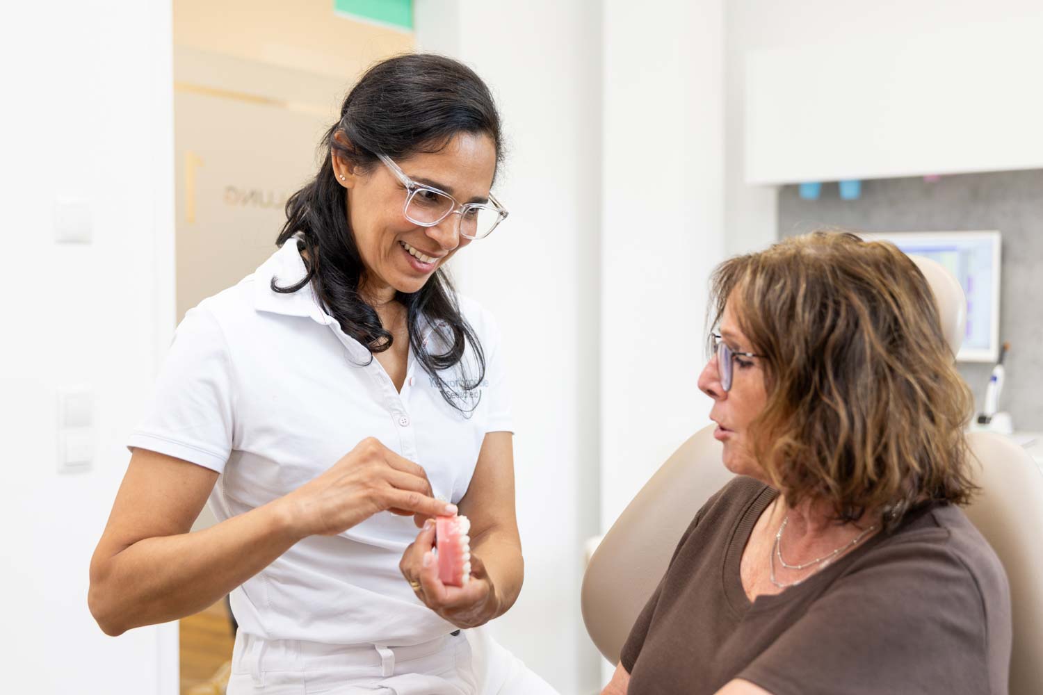 Kieferorthopädin Dr. Garcia erklärt einer erwachsenen Patientin am Gebissmodell die Zahnregulierung in der Fachpraxis Kieferorthopädie Seelscheid in Neunkirchen-Seelscheid.