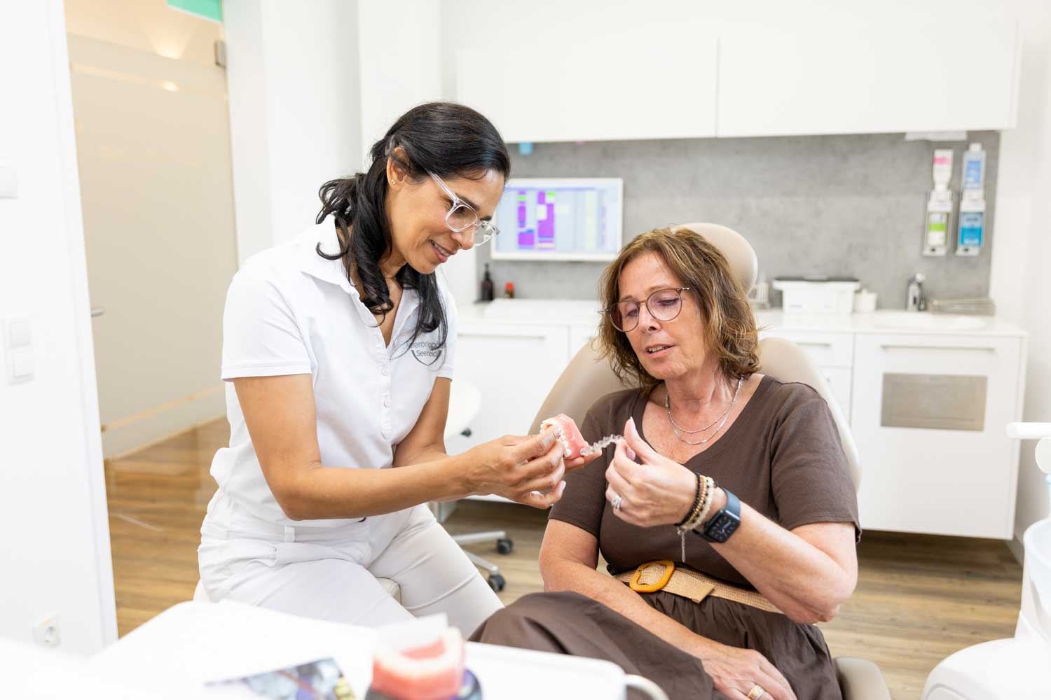 Kieferorthopädin Dr. Garcia erklärt einer erwachsenen Patientin eine transparente Invisalign-Schiene am Kiefermodell in der Praxis Kieferorthopädie Seelscheid in Neunkirchen-Seelscheid.