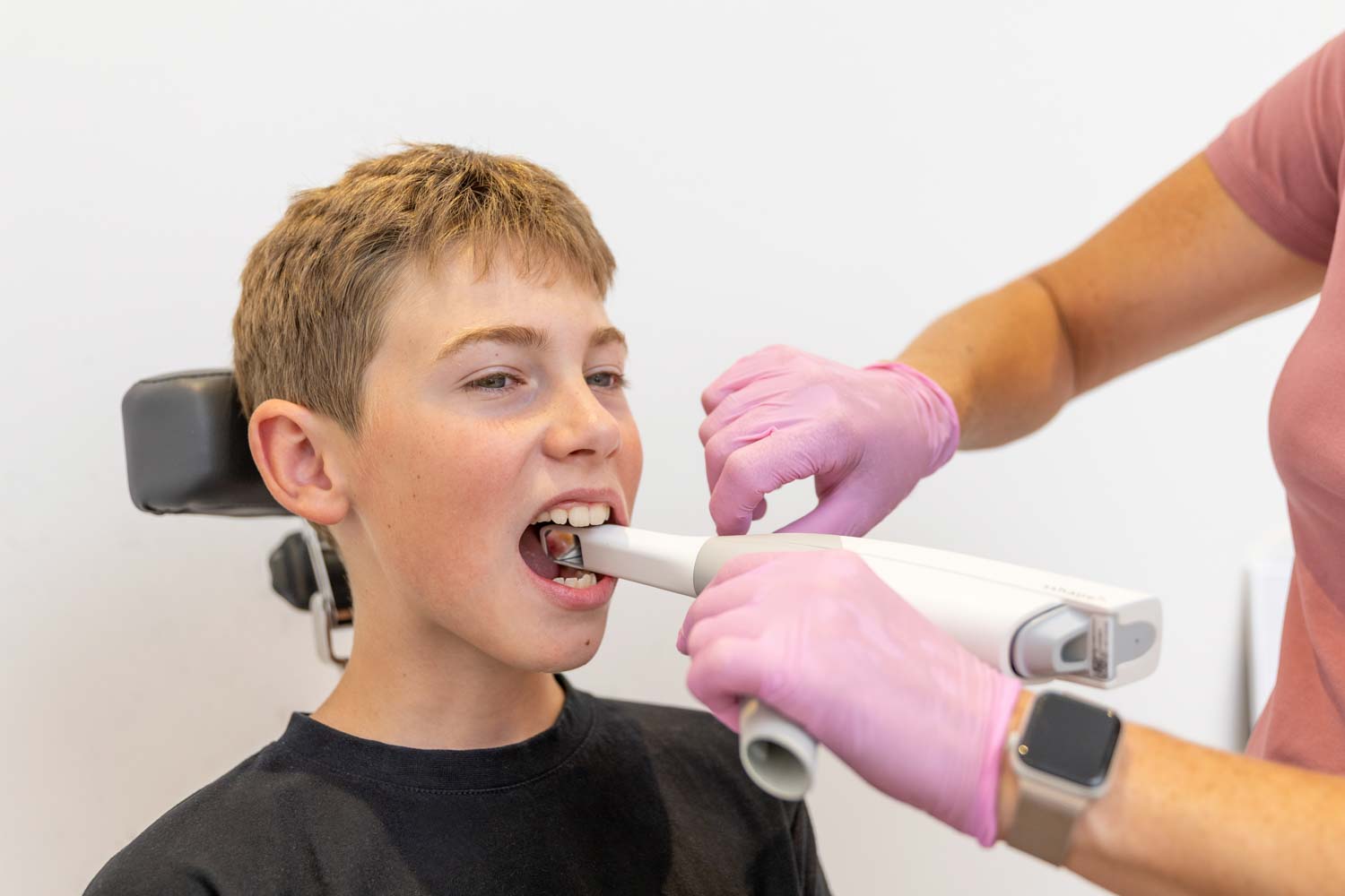 Mitarbeiterin führt bei einem jungen Patienten einen digitalen Intraoralscan mit Handscanner in der Praxis Kieferorthopädie Seelscheid in Neunkirchen-Seelscheid durch.