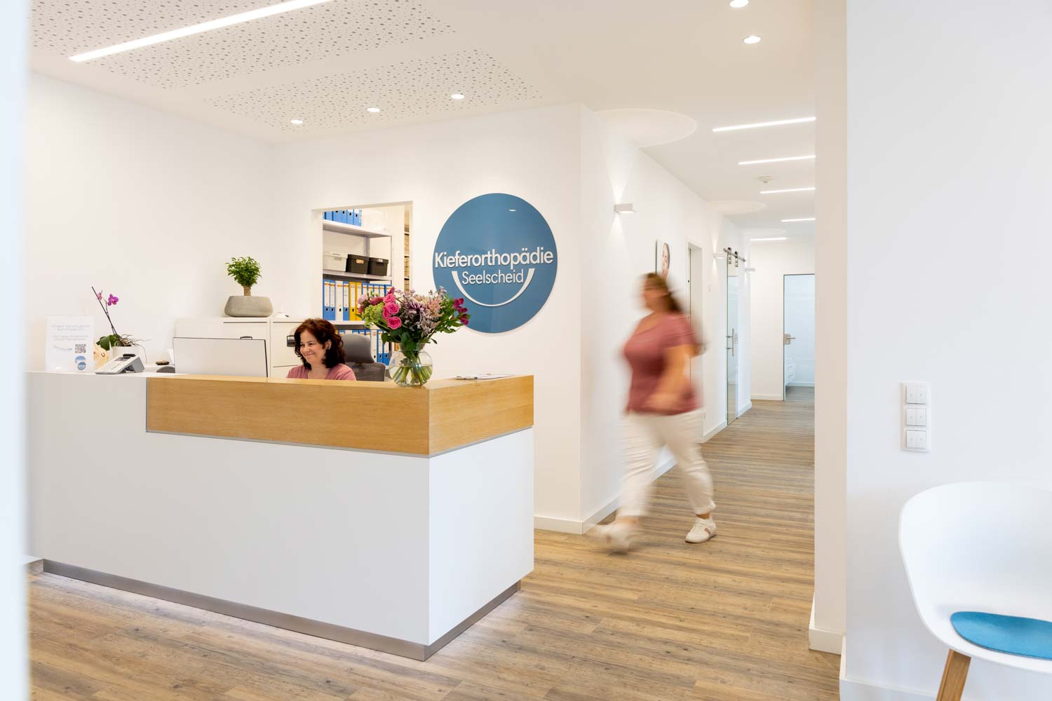 Moderner Empfangsbereich mit Praxistresen und beleuchtetem Logo in der Fachpraxis Kieferorthopädie Seelscheid in Neunkirchen-Seelscheid.